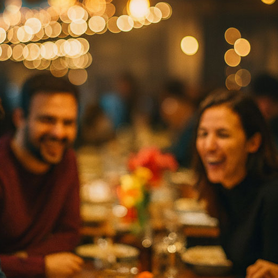 feiern-teaser Freunde genießen eine fröhliche Zeit bei einem Abendessen mit warmem Licht und festlicher Atmosphäre.