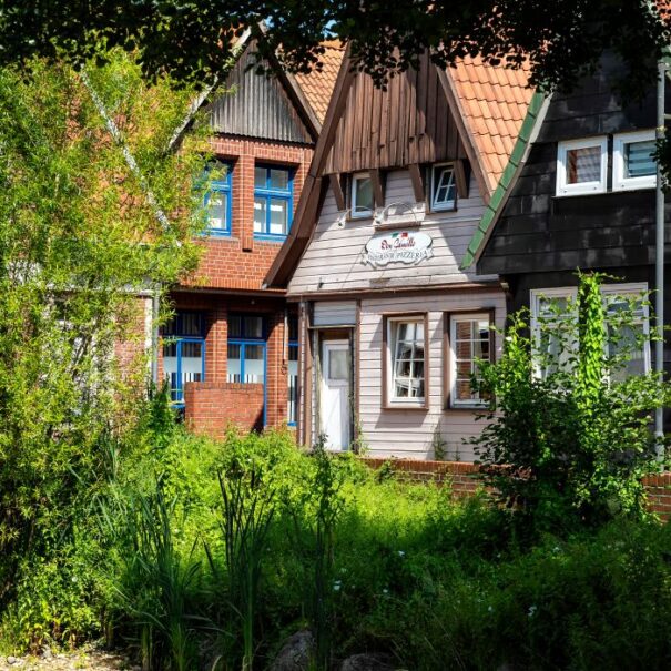 Restaurants_Soltau_section Bunte Fachwerkhäuser umgeben von üppigem Grün in einer ruhigen Wohngegend, ideal für entspannte Spaziergänge.