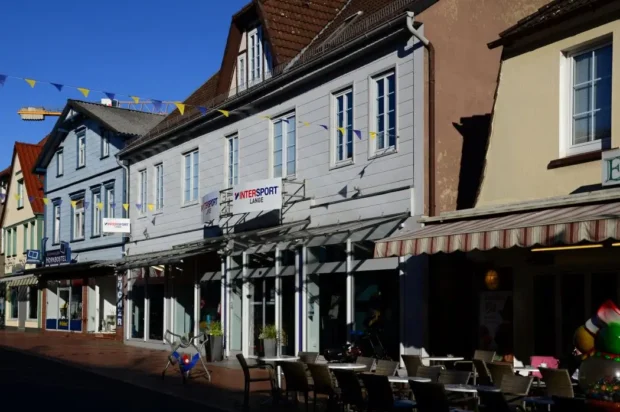 Restaurants_Soltau_header Bunte Geschäfte und Cafés in einer malerischen Straße mit Sonnenschein und blauen Himmel in Deutschland.