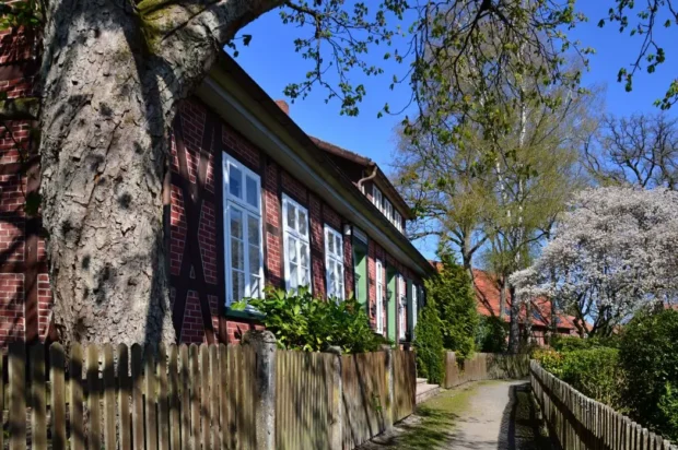 Restaurants_Faßberg_hero Ein malerisches Haus mit roten Ziegeln, umgeben von Bäumen und einem gepflegten Garten im Frühling.