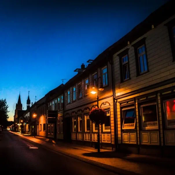 Restaurants_Walsrode_section Historische Altstadt mit Fachwerkhäusern und stimmungsvoller Straßenbeleuchtung in der blauen Stunde bei Nacht.
