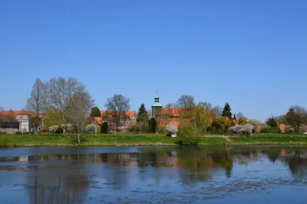 Restaurants_Walsrode_header Idyllische Ansicht einer historischen Stadt mit Kirche und See an einem sonnigen Frühlingstag mit blauem Himmel.