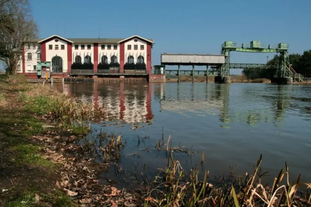 Restaurants_Hambühren_header Historisches Wasserkraftwerk am Fluss mit grüner Infrastruktur und reflektierender Wasseroberfläche.
